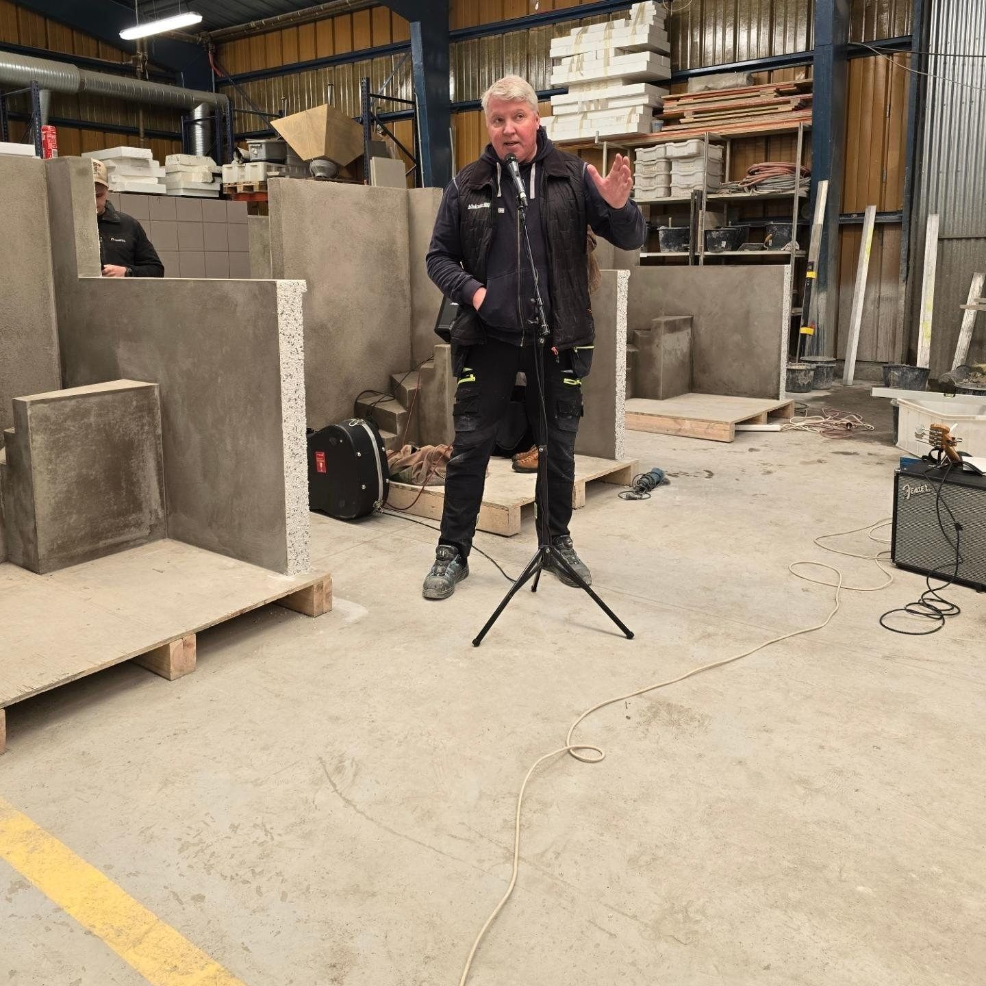 Maður stendur fyrir framan hljóðnema í vöruhúsi