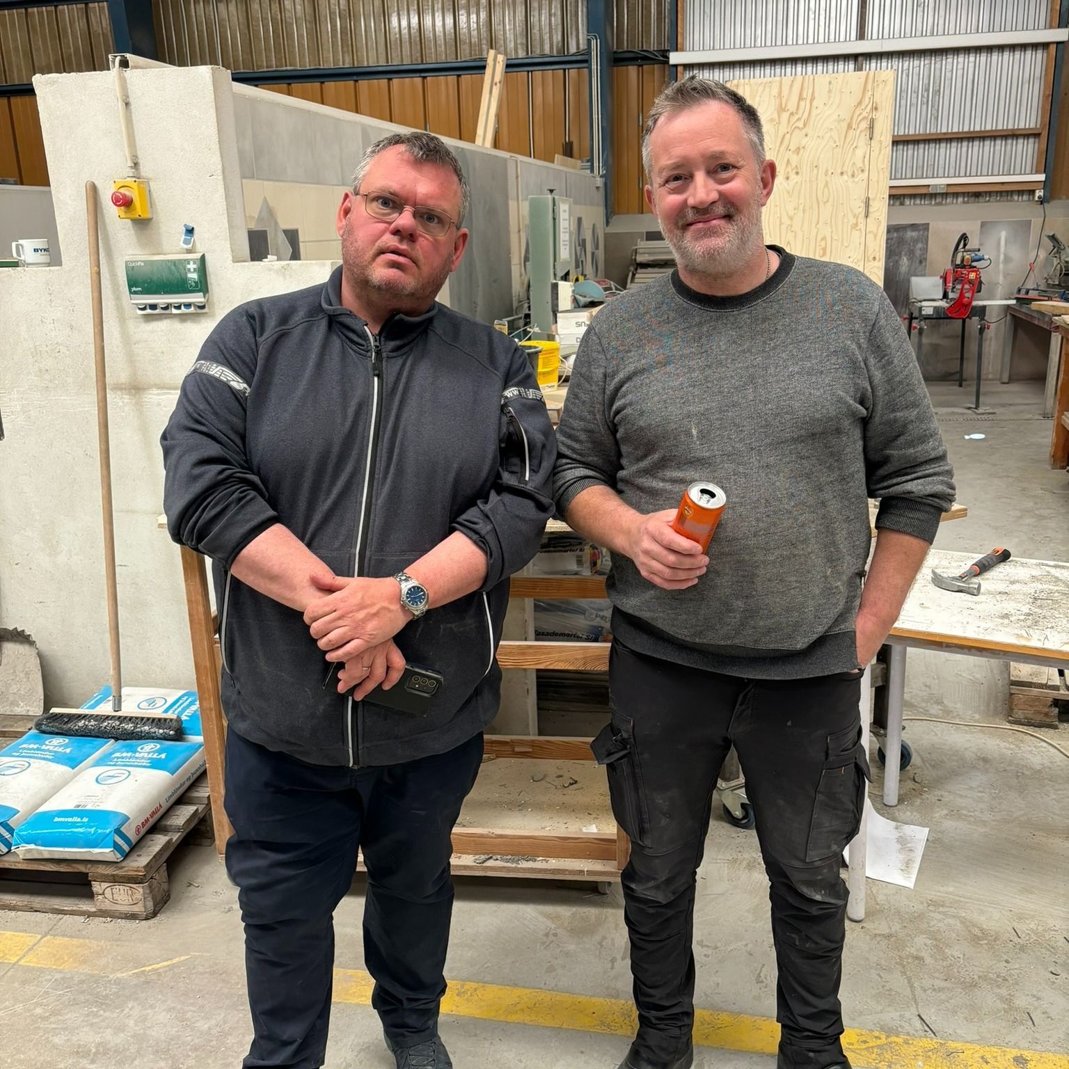 Tveir menn standa við hlið hvors annars í vöruhúsi