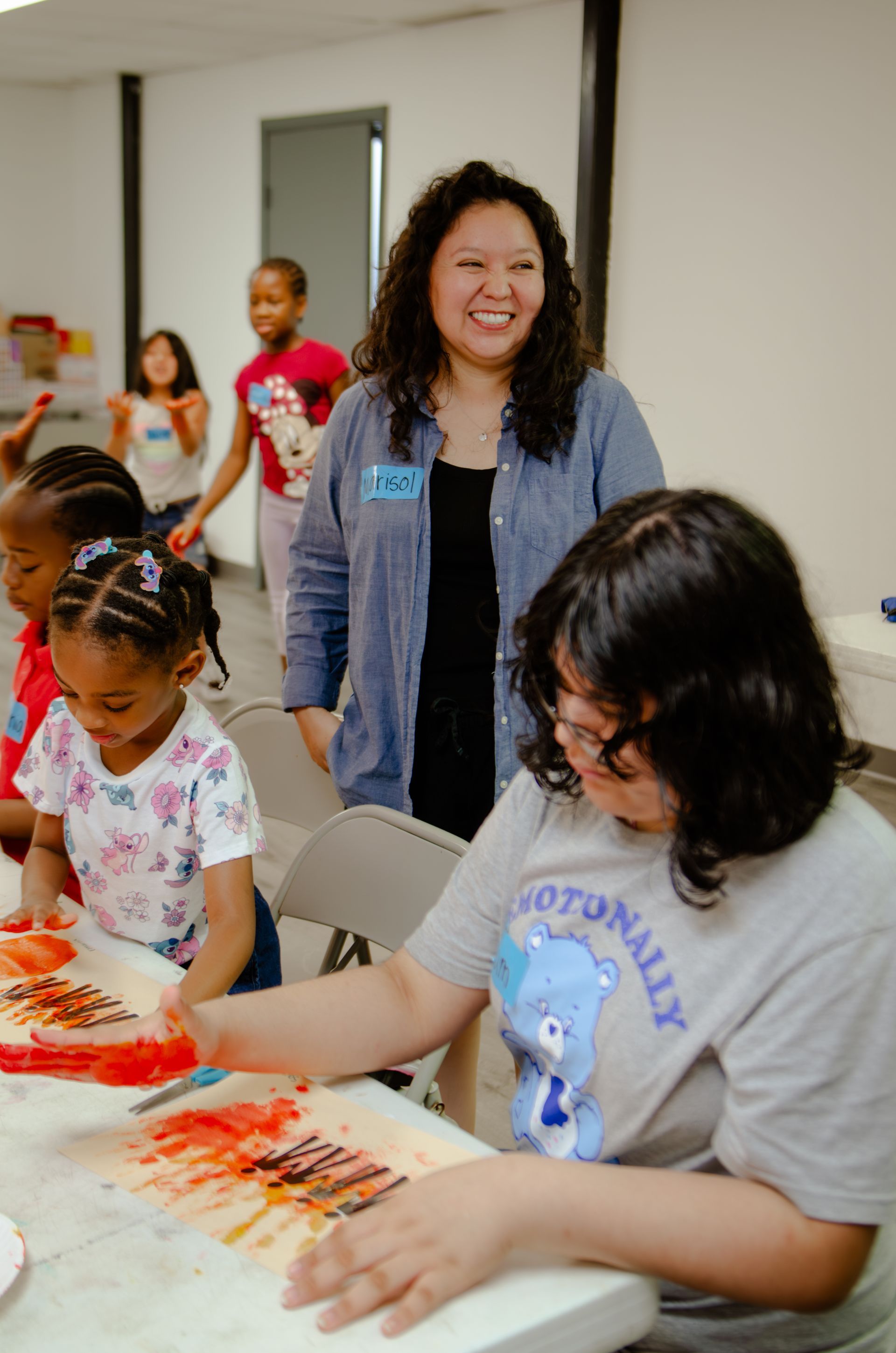 A woman is sitting at a table painting with children.