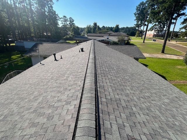 Overhead view of a gray shingle roof on a house, sunny outdoors.