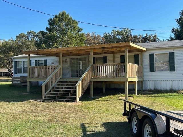 Mobile home with a newly constructed wooden porch, deck, and roof.