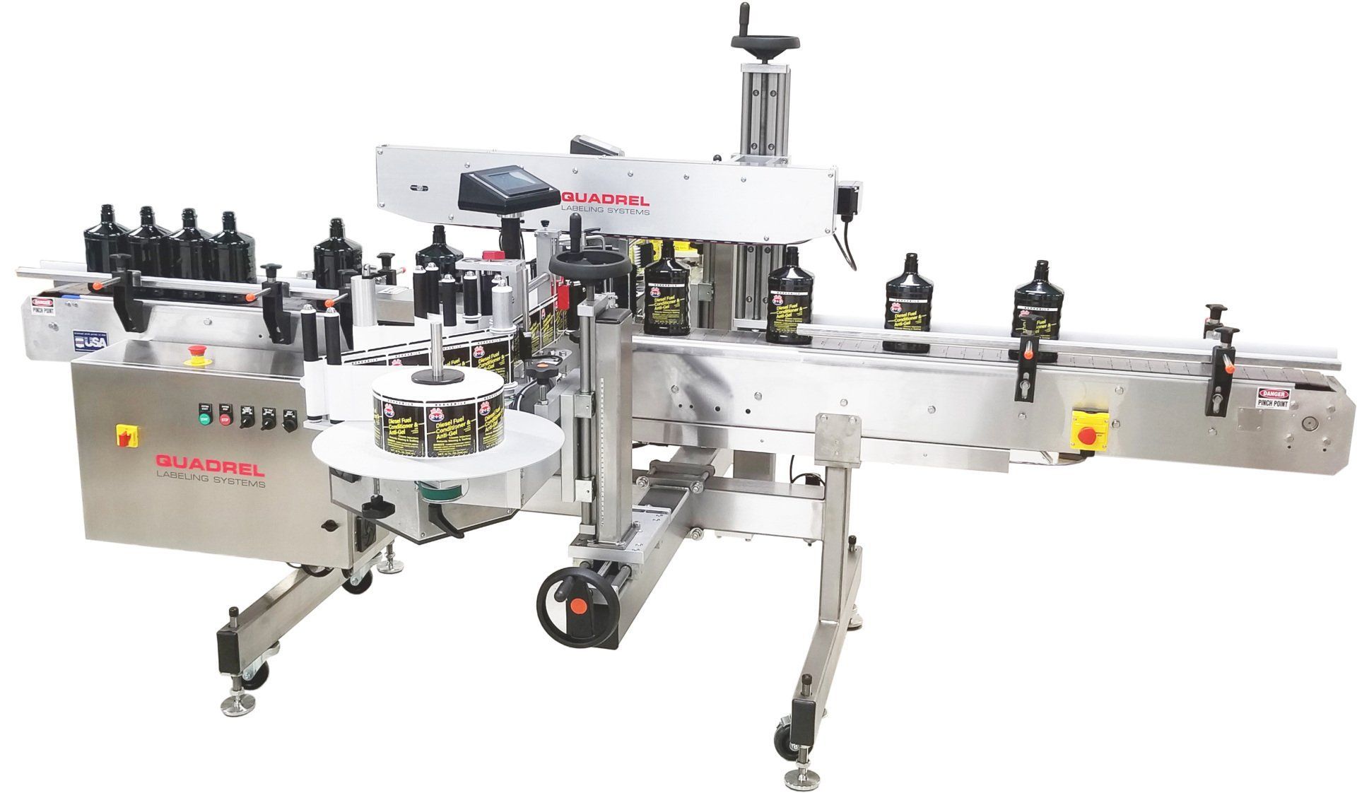 An industrial labeling machine with bottles moving along a conveyor belt in a manufacturing facility.