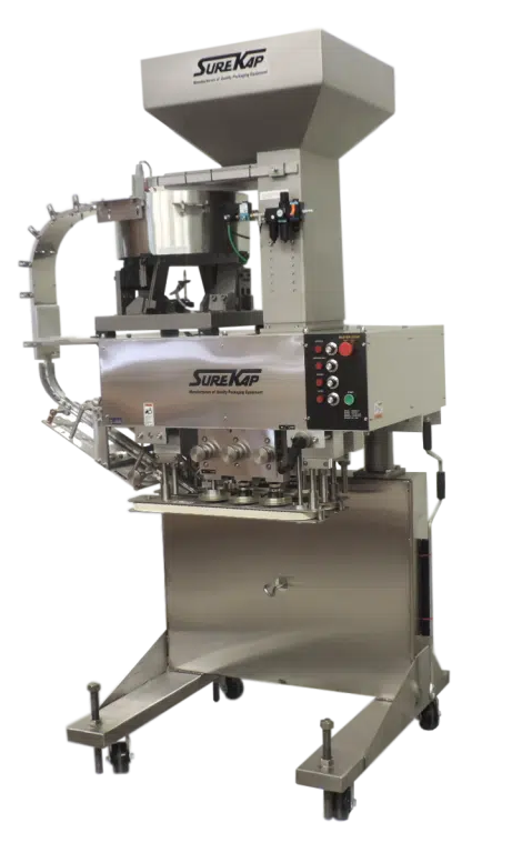 A stainless steel cup filling and sealing machine with a top-mounted hopper and control panel on a wheeled base.