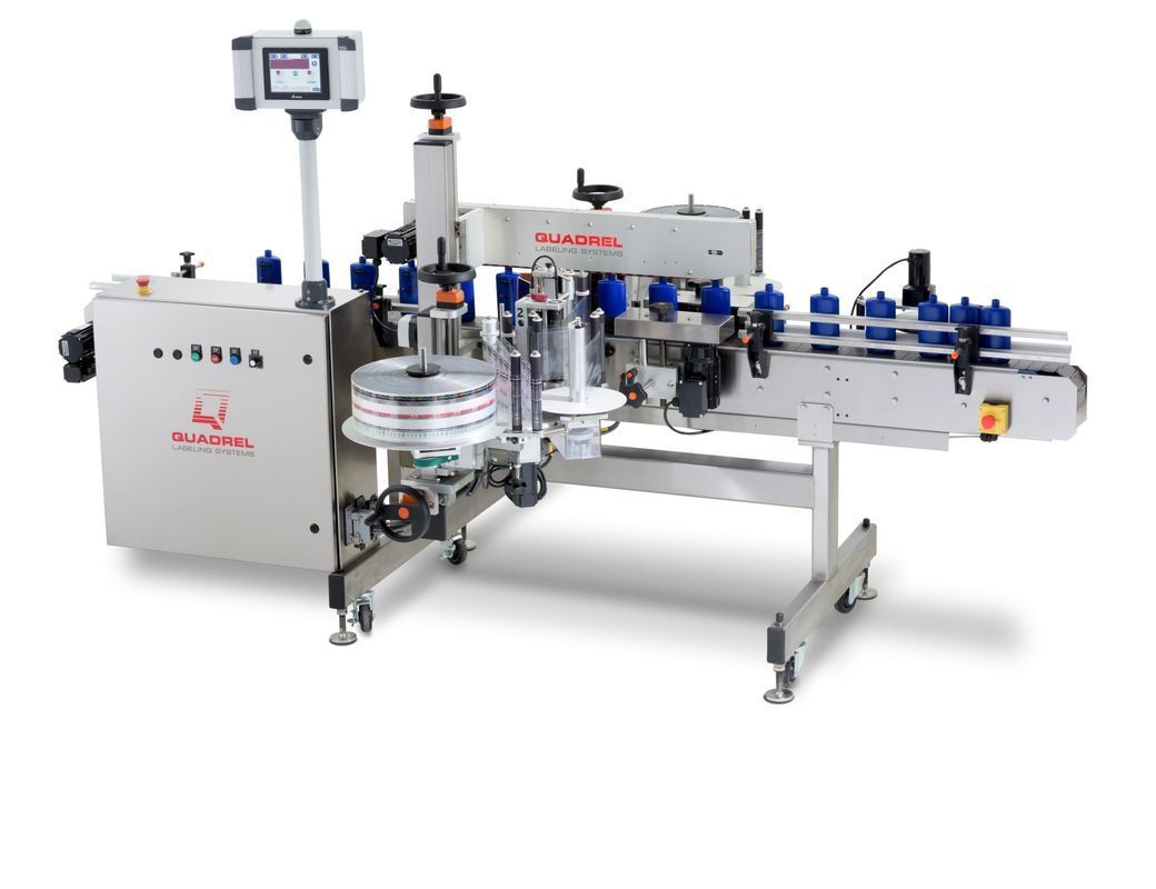 An industrial labeling machine with a conveyor belt carrying blue bottles.