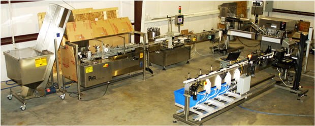 A stainless-steel industrial bottling and labeling assembly line.