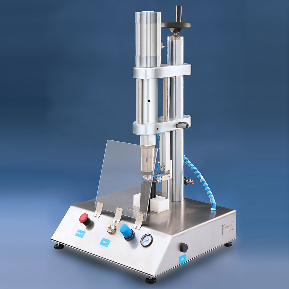 A pneumatic benchtop ultrasonic welding machine with a protective plastic shield on a stainless steel base.