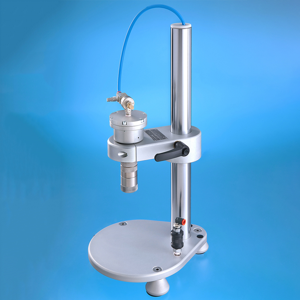 A silver pneumatic press stand with a circular base, vertical column.