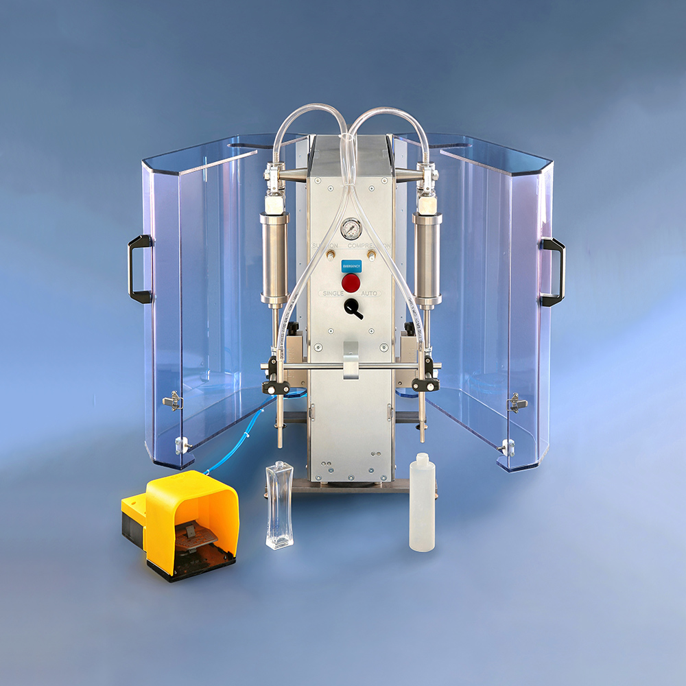A dual-nozzle, pneumatic liquid filling machine with protective clear side shields and a yellow foot pedal on a blue floor.