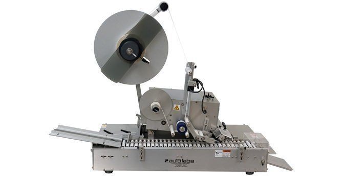 Industrial automatic labeling machine with a silver metal base.