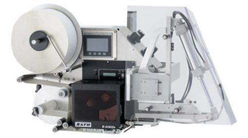 An industrial label printer and applicator machine with a large supply roll on the left and a mechanical arm.