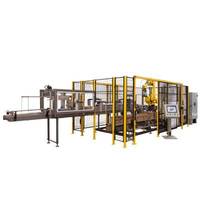 An industrial robotic packaging system with a yellow mechanical arm inside a protective metal cage on a factory floor.
