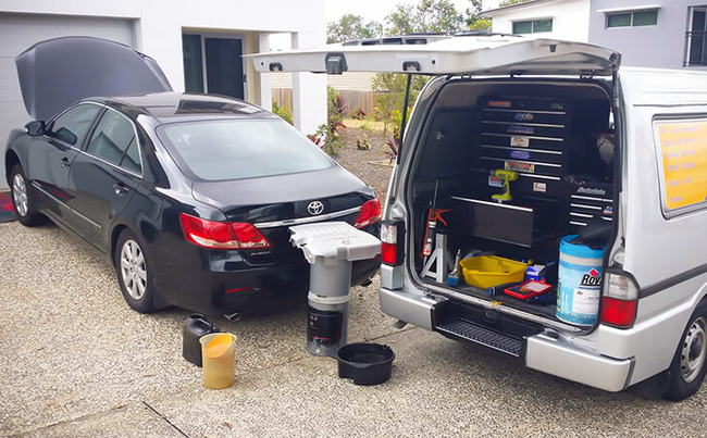 A black car is parked next to a white van with the trunk open.