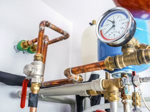 A close up of a plumbing system with copper pipes and a pressure gauge.