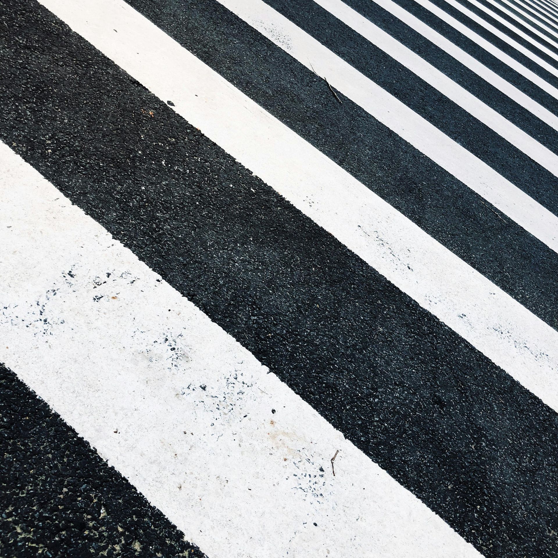 A black and white striped crosswalk with a diagonal pattern