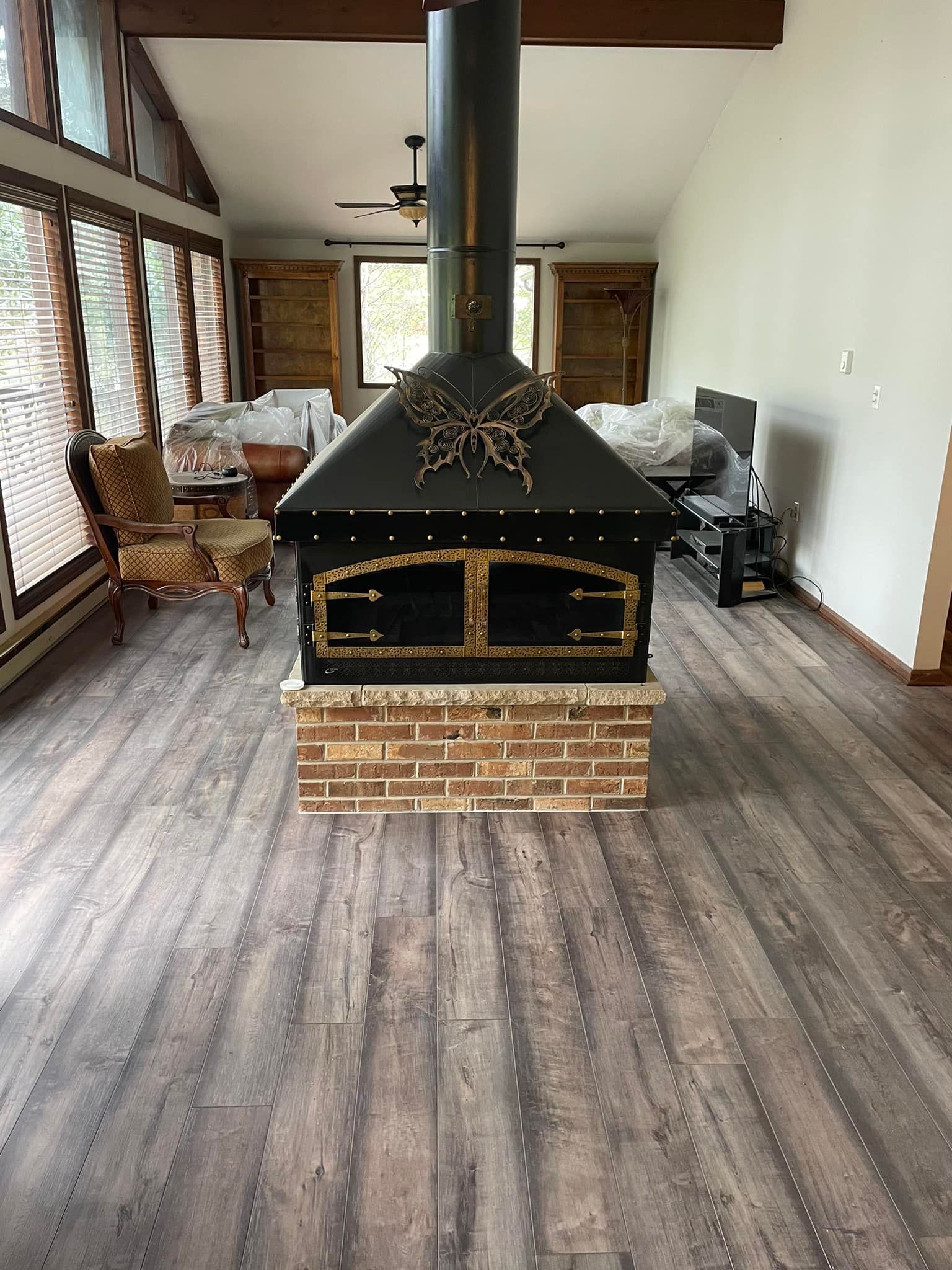 There is a fireplace in the middle of the room with new hardwood floors by Floor Source