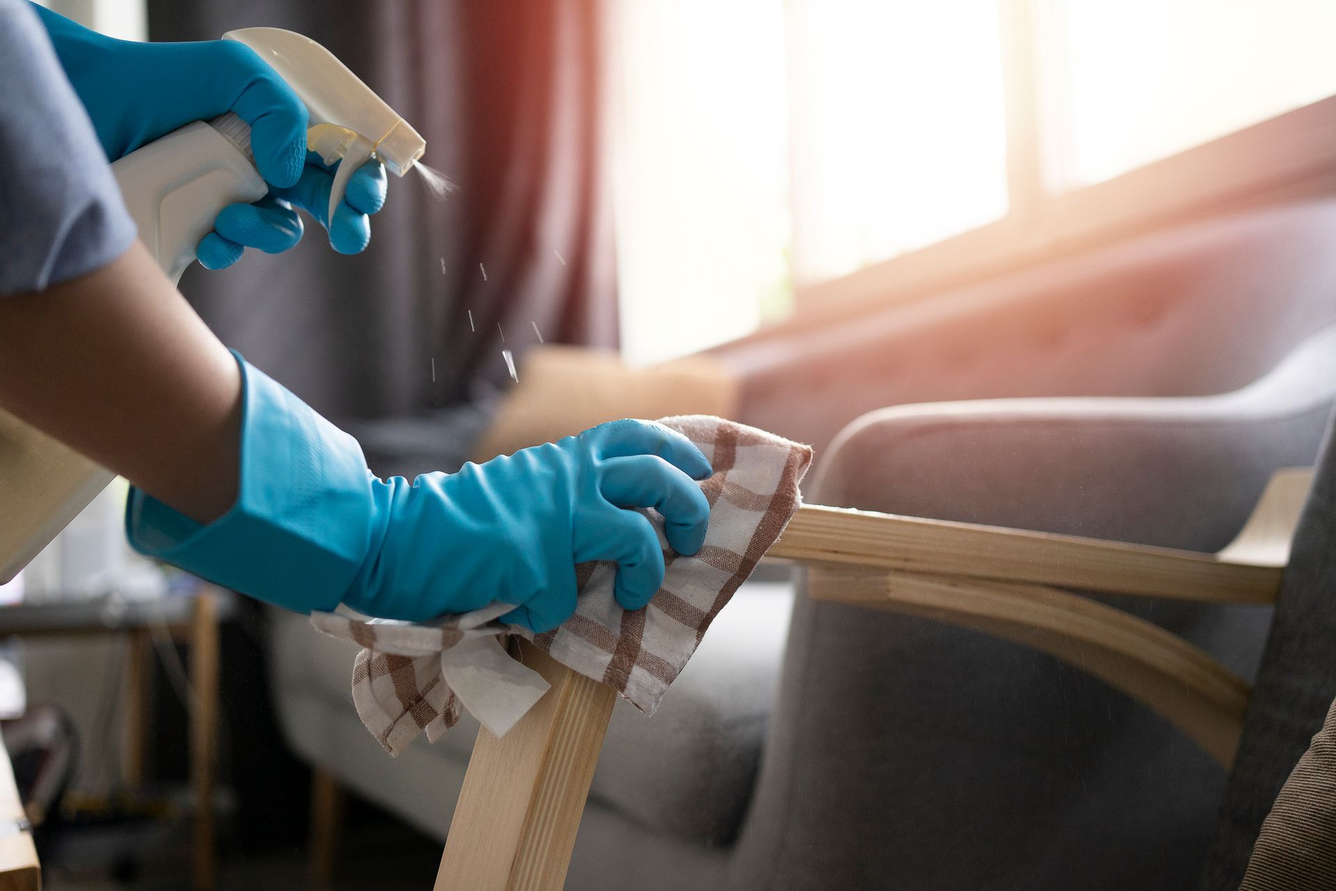 A person wearing blue gloves is cleaning a chair with a cloth.