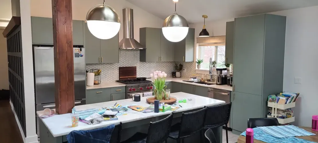 Kitchen with green cabinets, stainless steel appliances, and a large island.