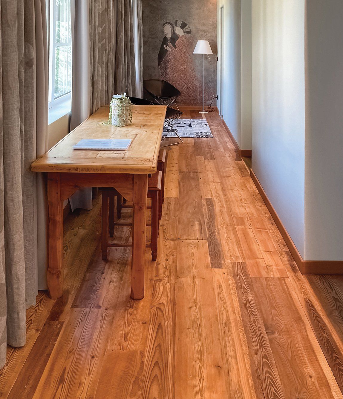 Una lunga scrivania in legno in uno stretto corridoio con pavimenti in legno