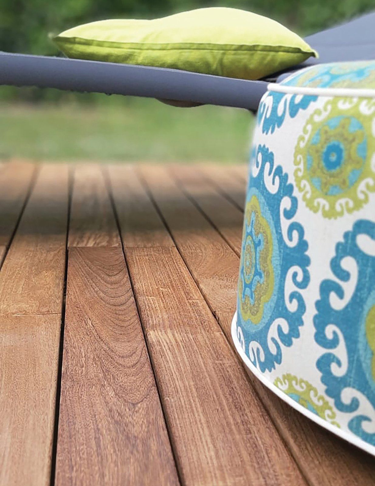 Terrazza in legno con pouf decorato e cuscino verde.