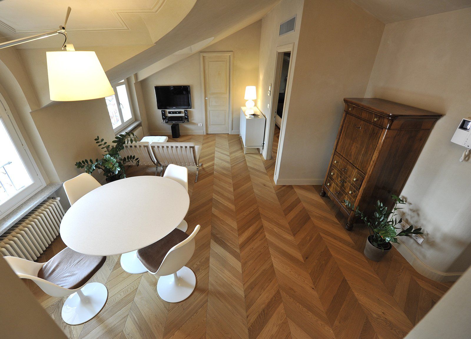 Uno spazio abitativo luminoso e moderno con un tavolo rotondo, pavimenti in legno e una cassettiera alta.