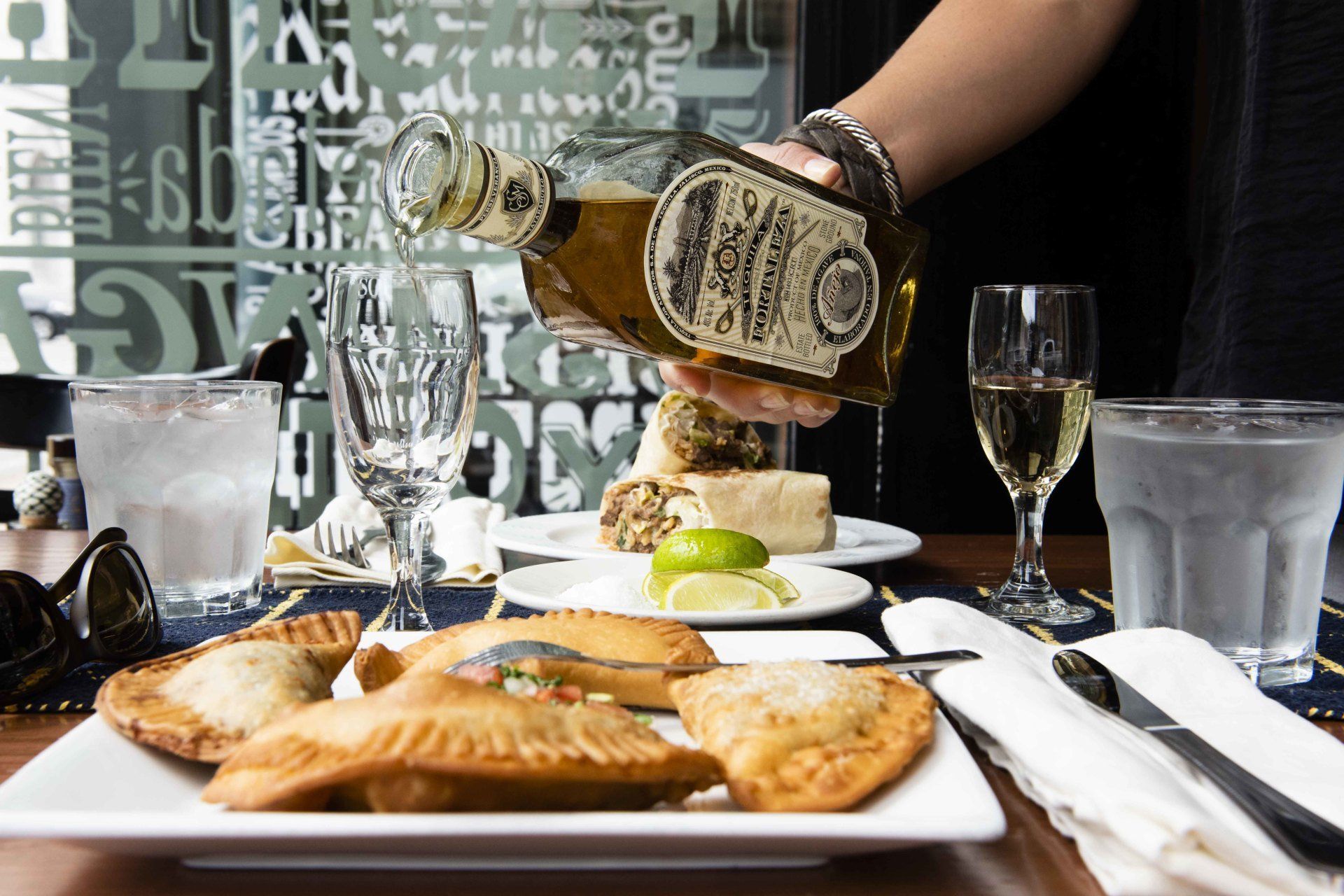 A person pouring a bottle of tequila into a plate of food