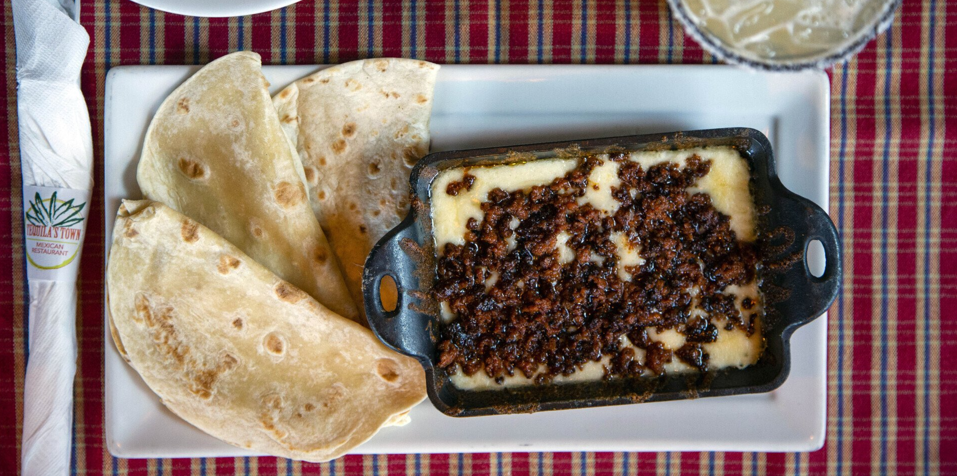 A white plate topped with a casserole and tortillas on a table.