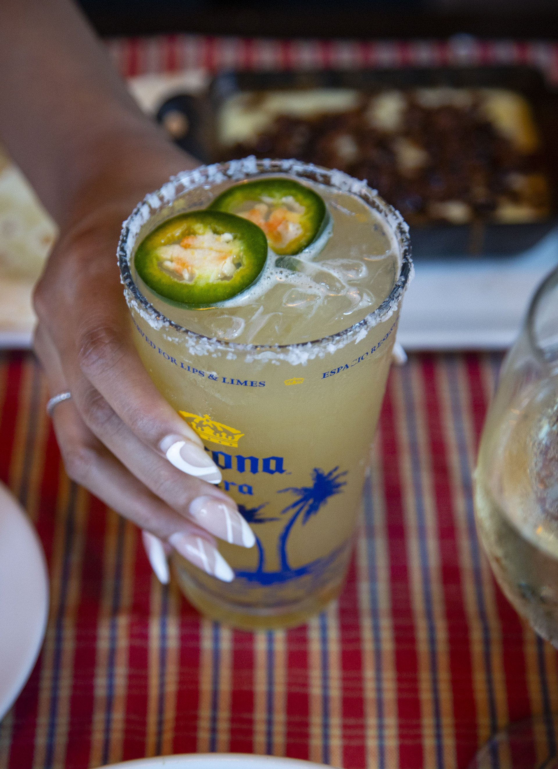 A person is holding a corona drink with jalapenos in it