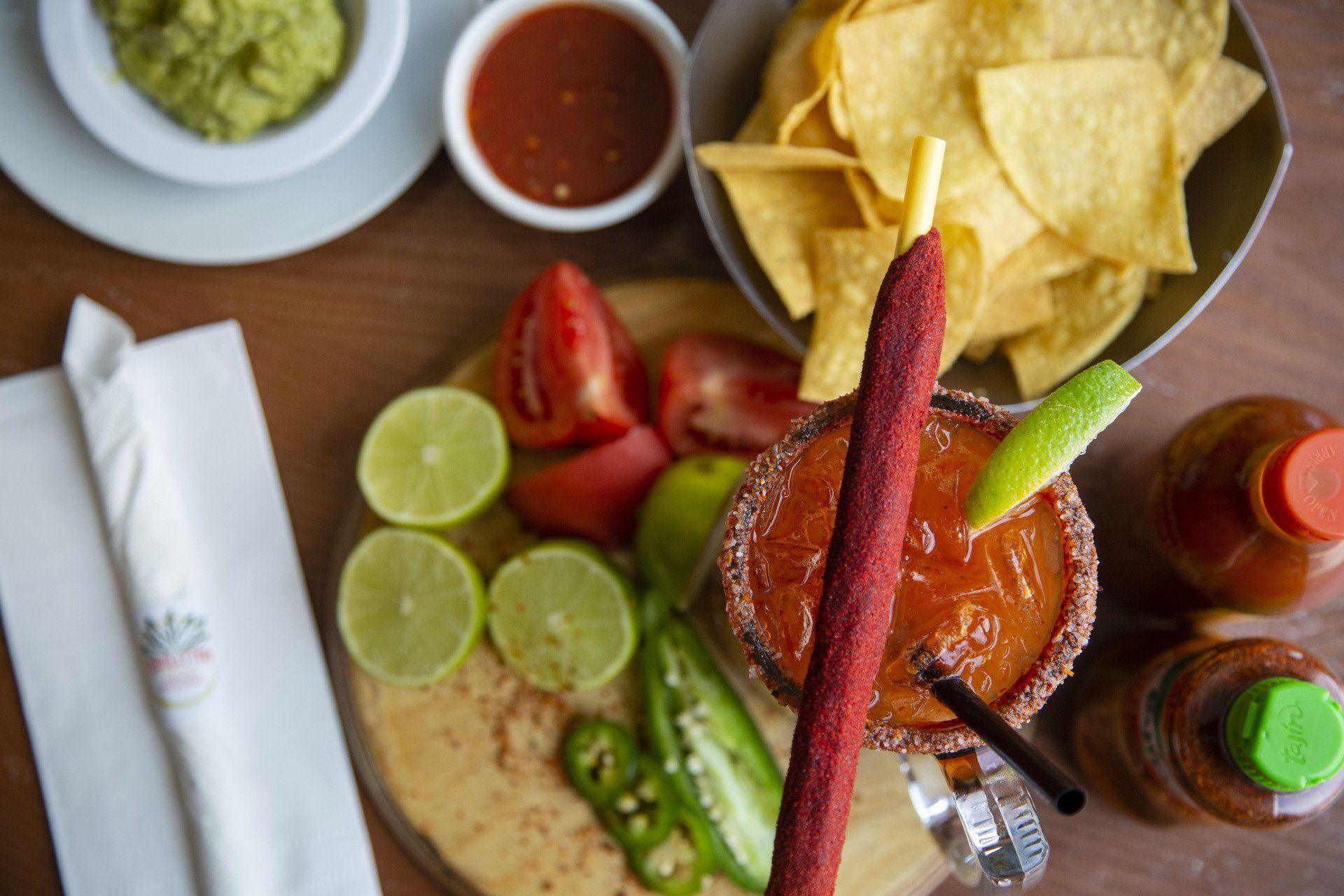 A table topped with a margarita , tortilla chips , guacamole and salsa.