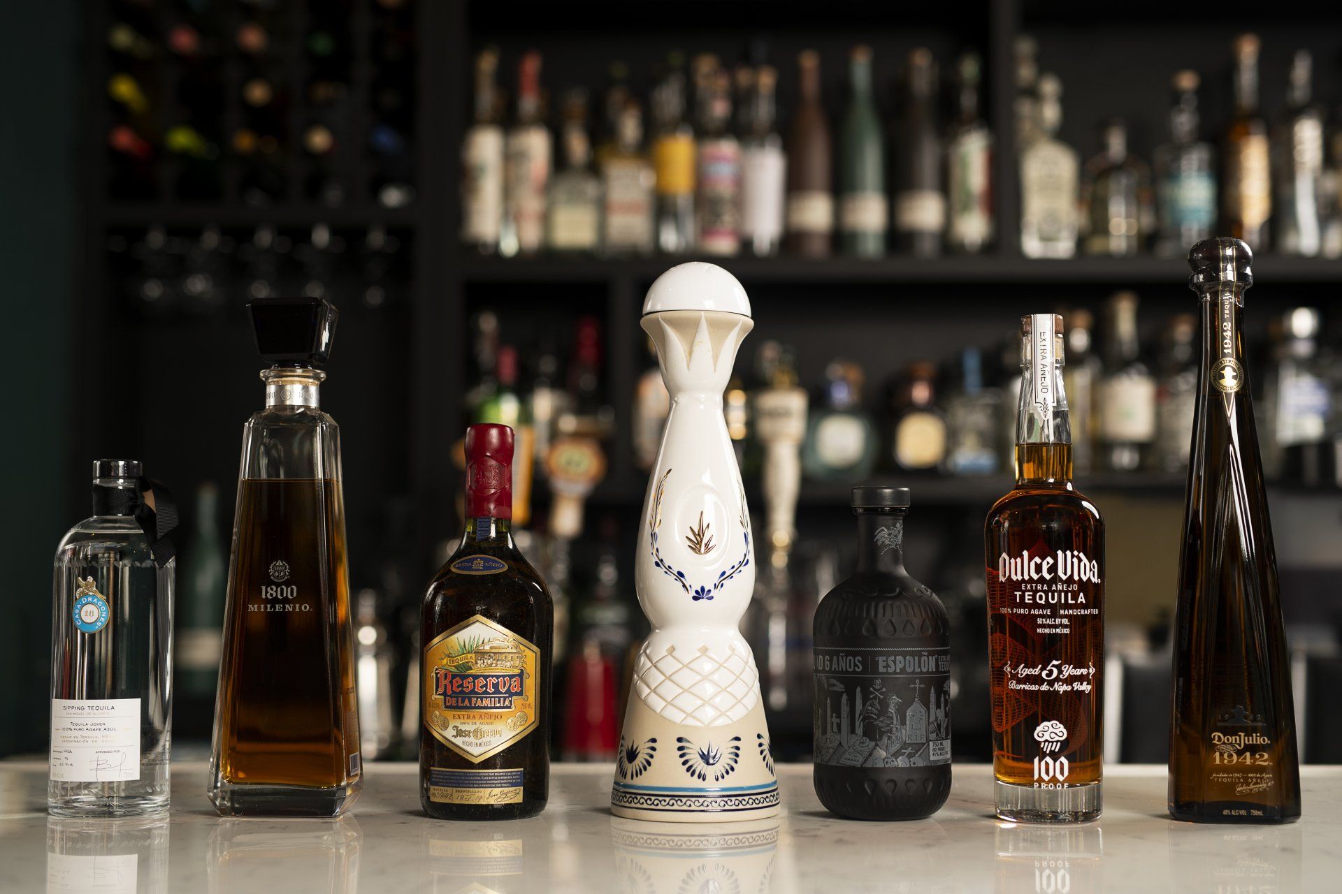 A row of liquor bottles are lined up on a bar counter.