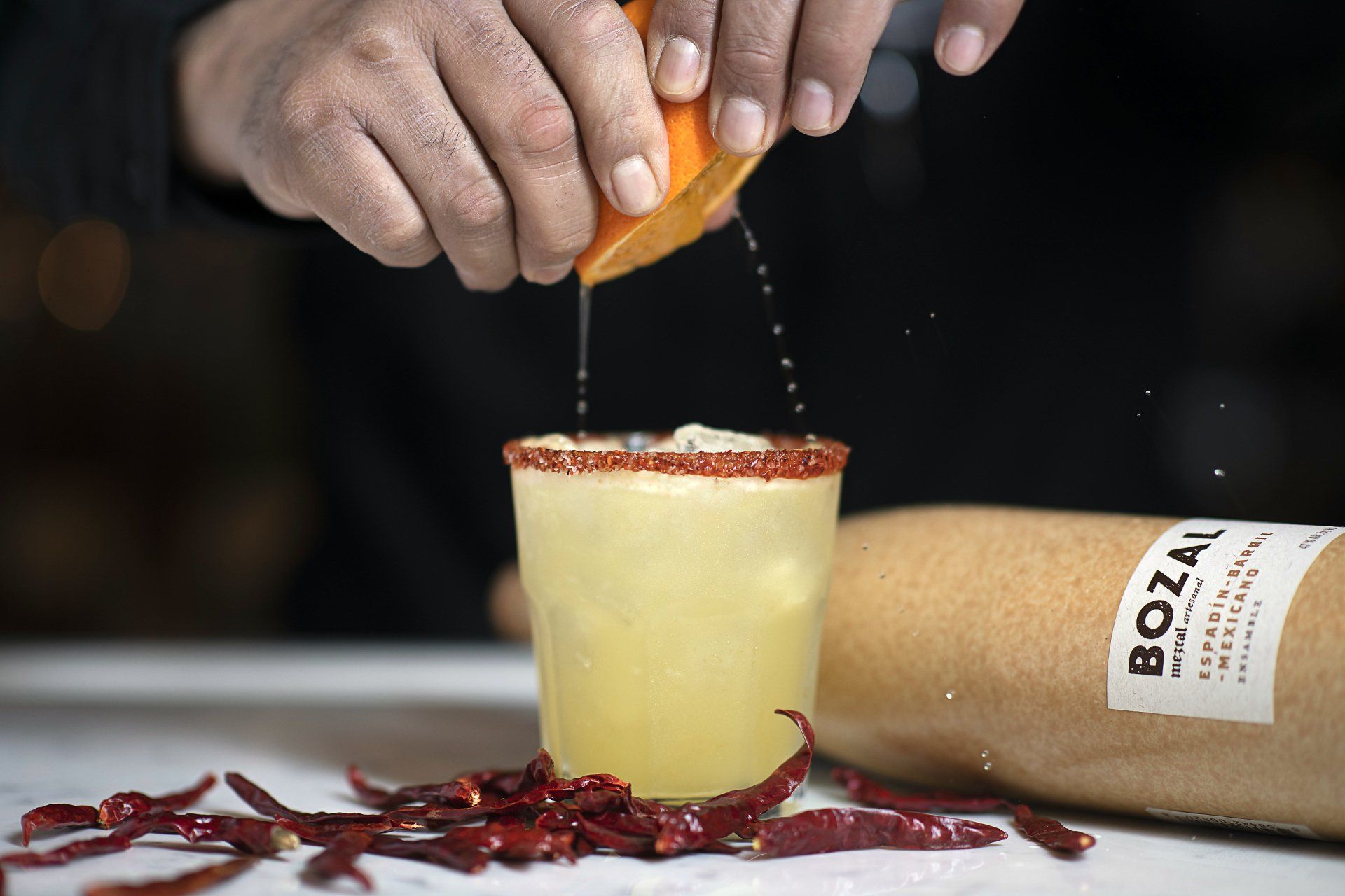 A person is pouring orange juice into a glass of liquid.