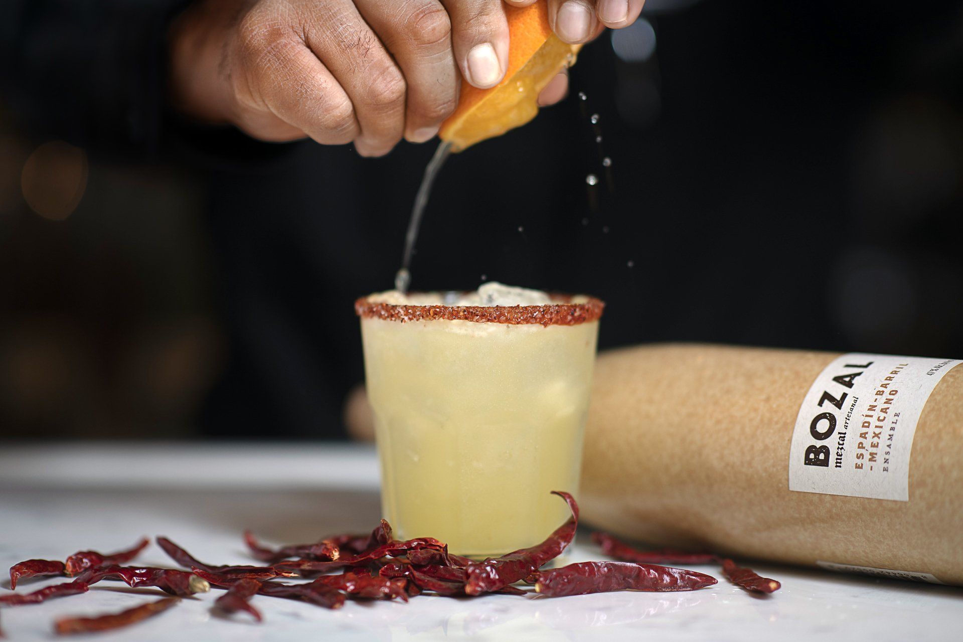 A person is squeezing an orange into a drink.