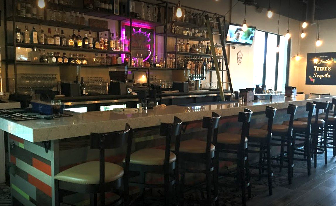 A long bar with a lot of chairs in a restaurant.