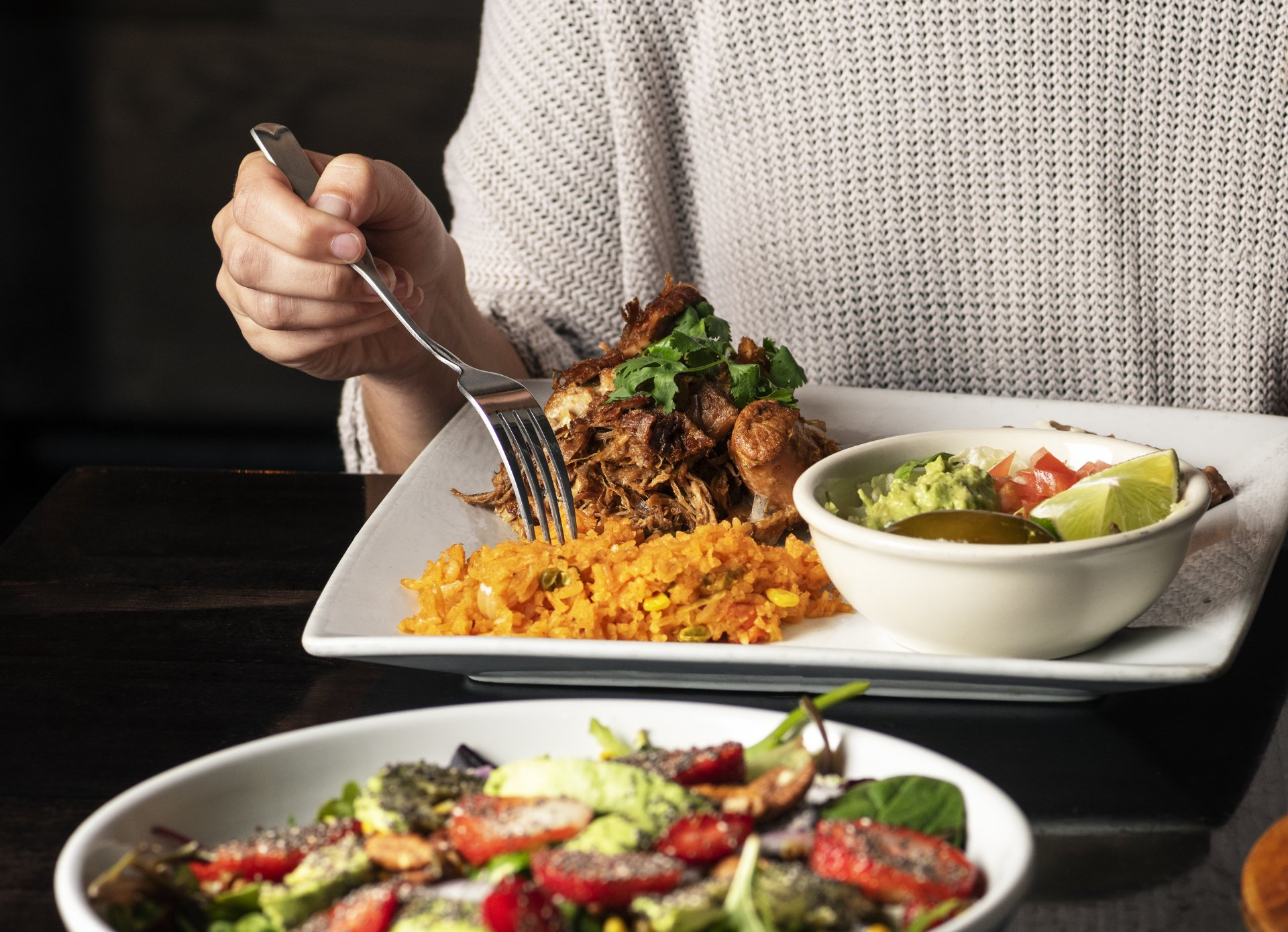 A person is eating a plate of food with a fork.
