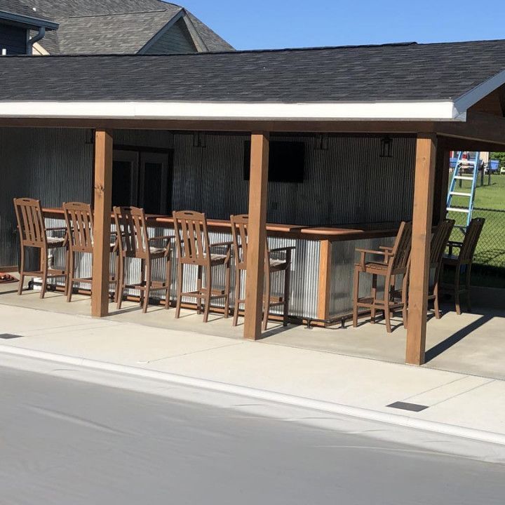 A covered patio area with a bar and chairs