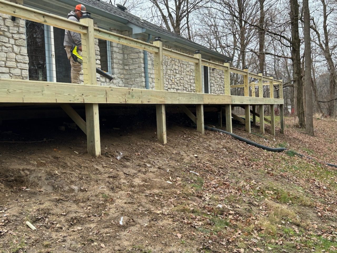 A wooden deck is being built in front of a stone house.