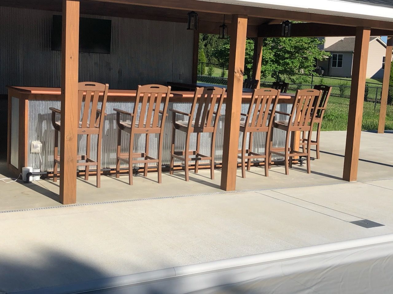 A patio with a bar and chairs under a canopy.