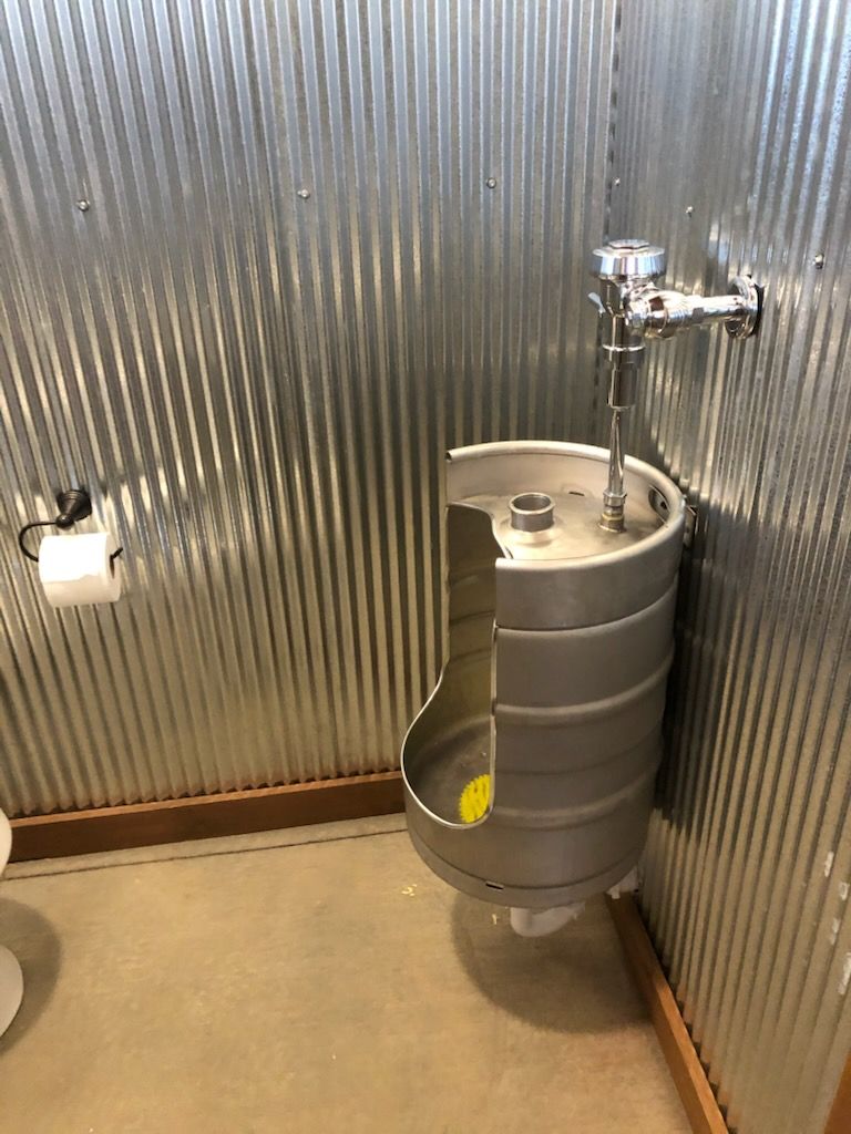 A bathroom with a urinal made out of a beer keg.