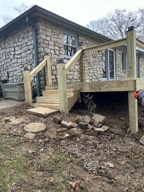 A wooden deck is being built in front of a stone house.