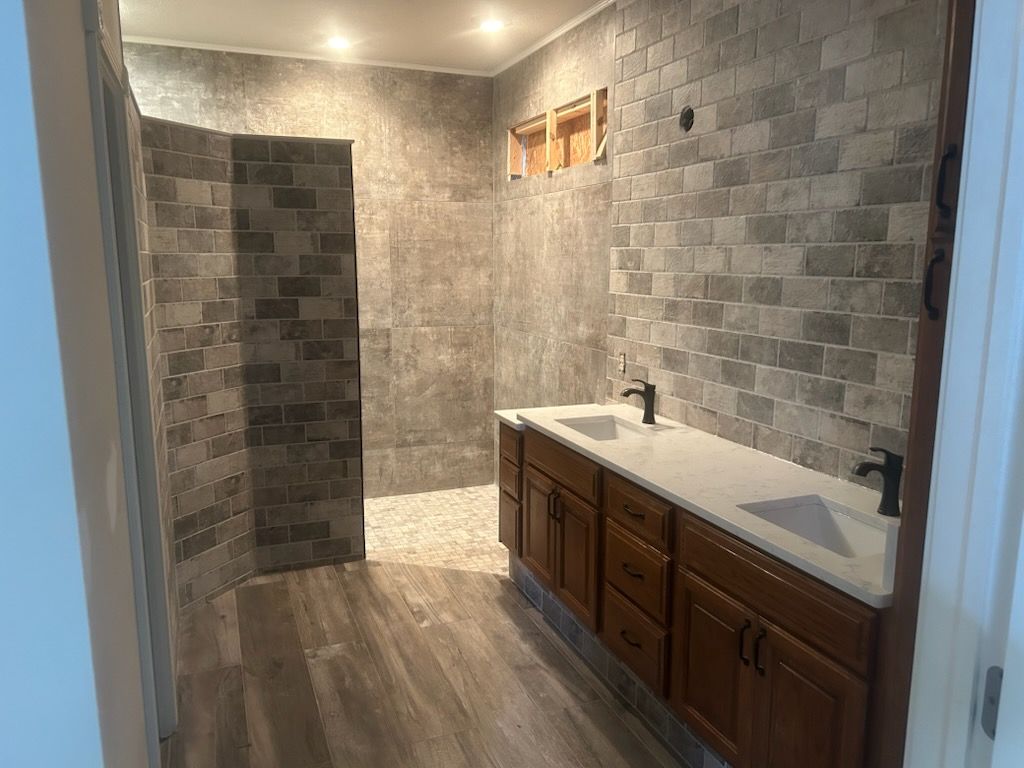 A bathroom with two sinks and a walk in shower.