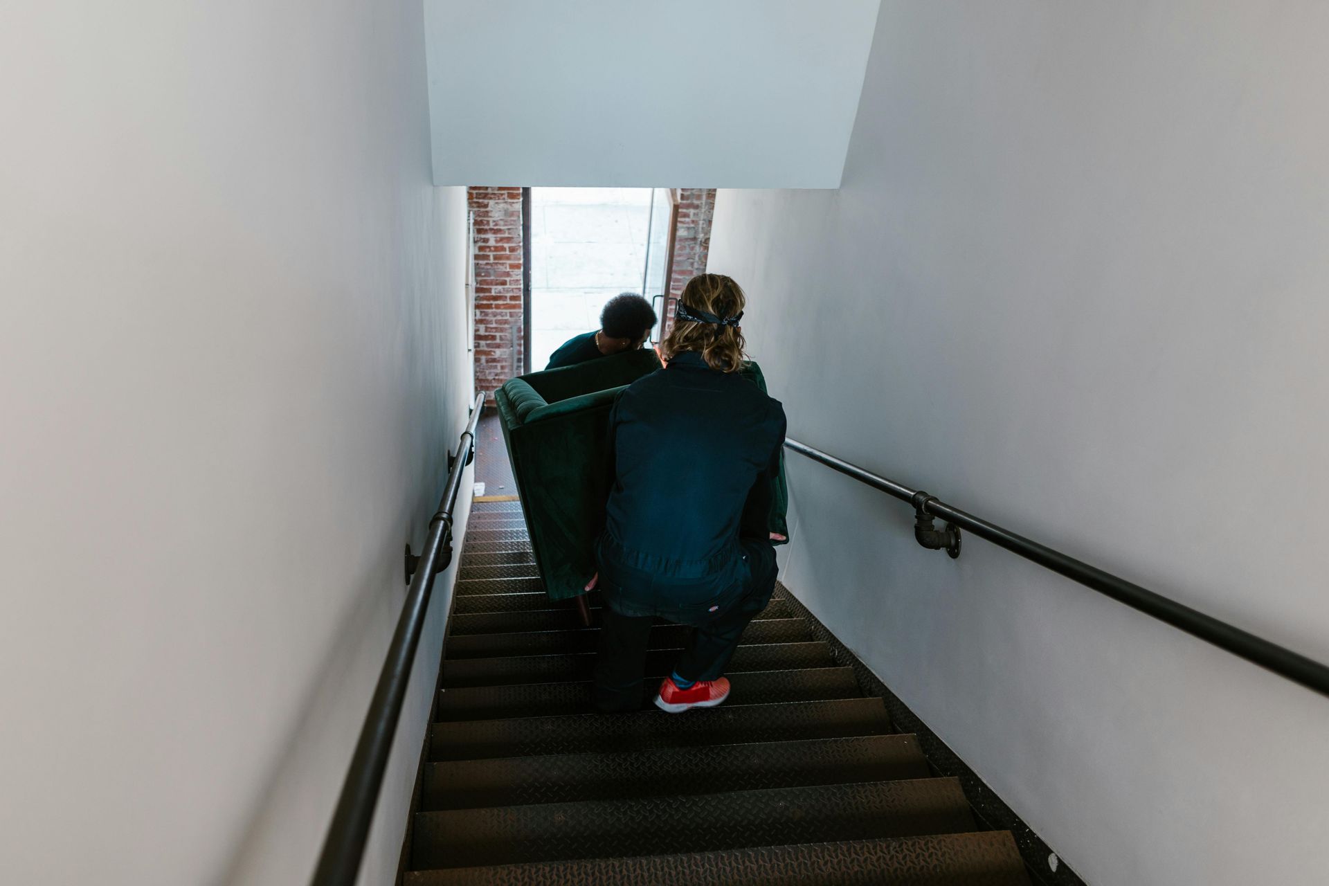 A man and a woman are carrying a couch up a set of stairs.