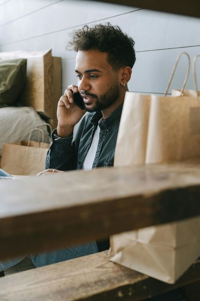 A man is sitting at a table talking on a cell phone.