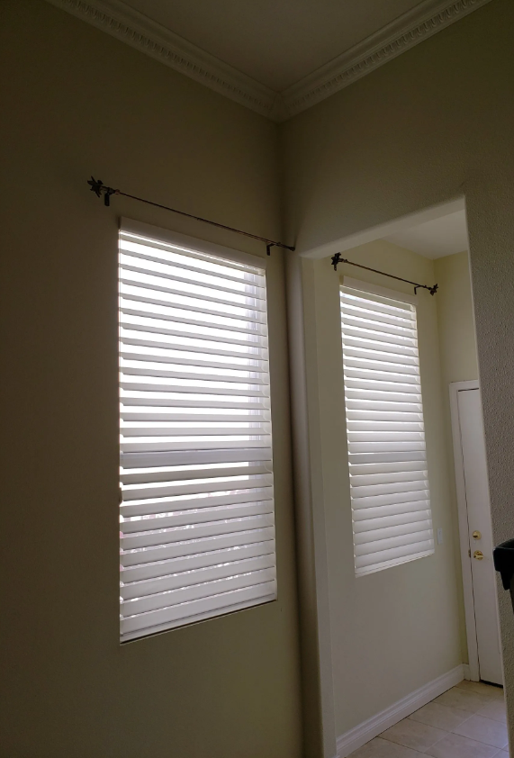A room with two windows with blinds on them.
