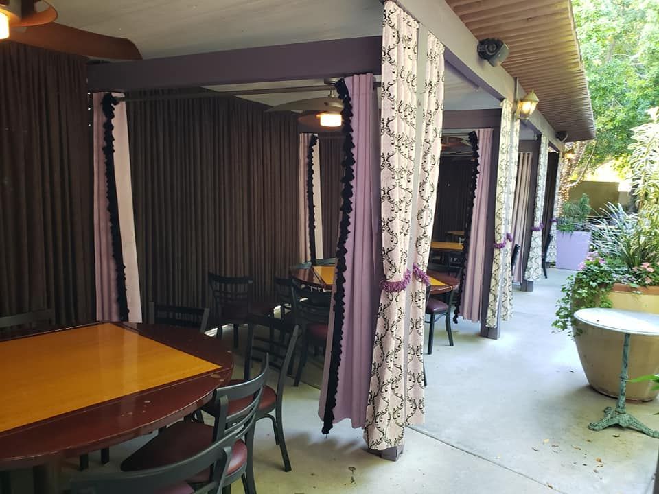A patio with tables and chairs and purple curtains