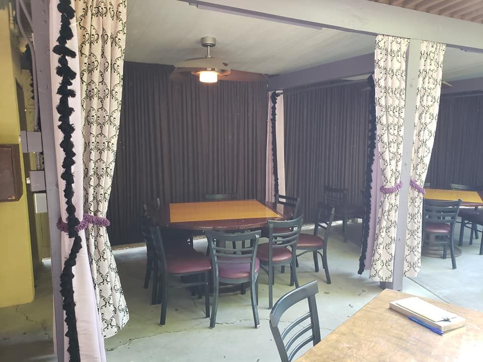 A dining room with tables and chairs and purple curtains