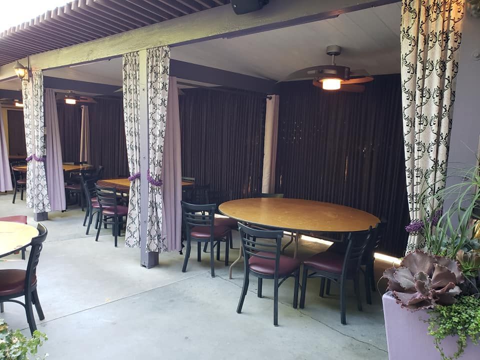 A restaurant with tables and chairs under a canopy with purple curtains.