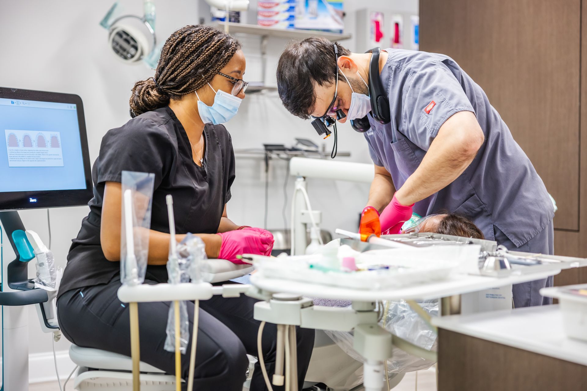 Man in dental chair smiles as dentist examines his teeth.