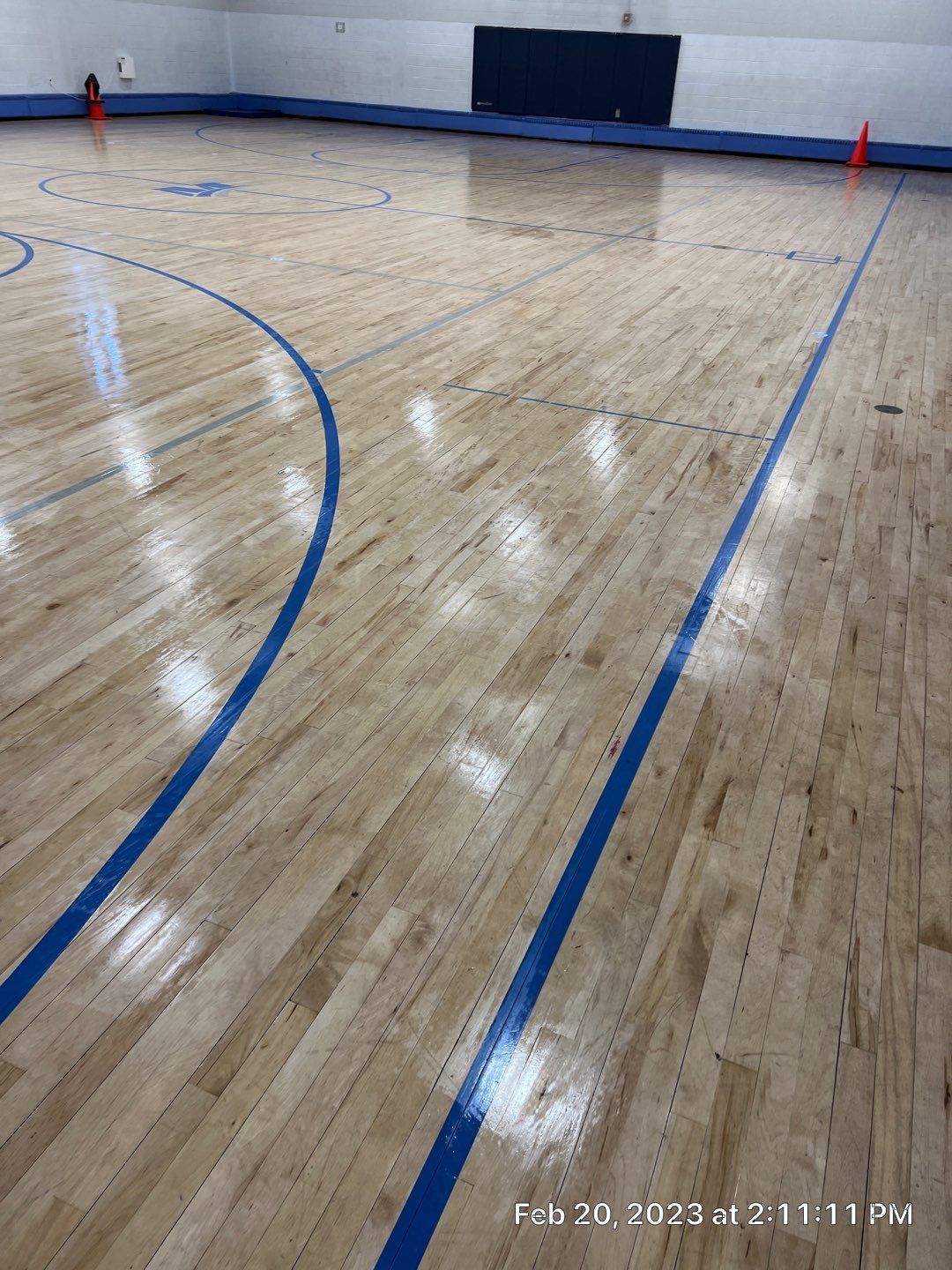 A basketball court with a wooden floor and blue lines.