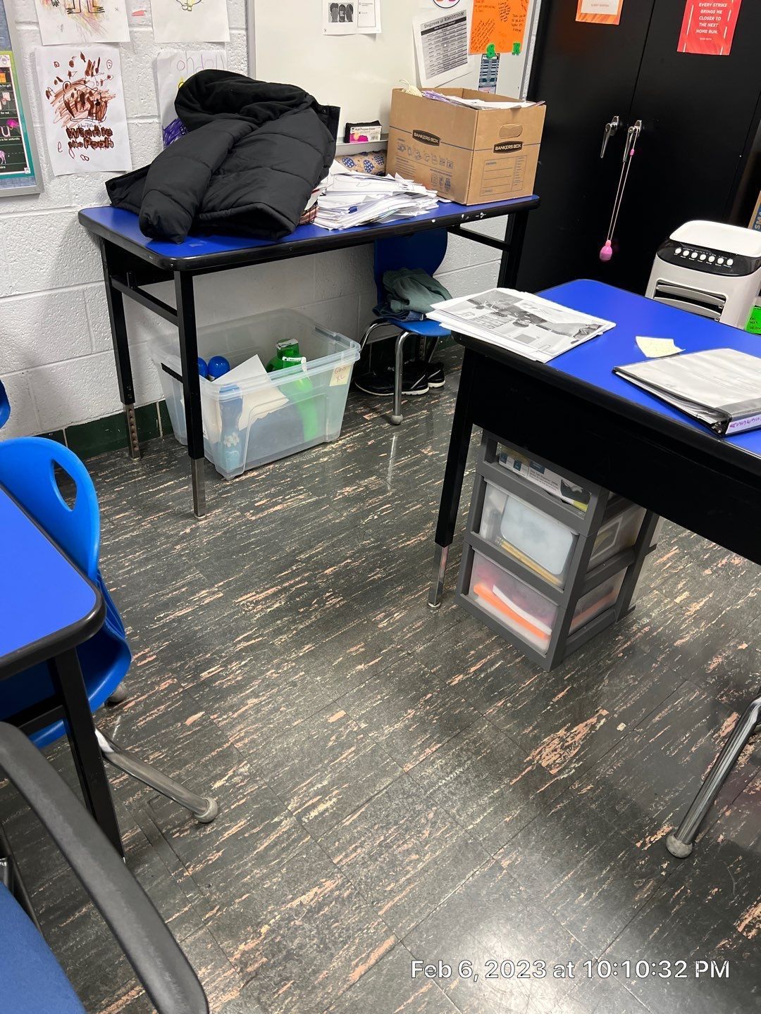 A classroom with blue desks and chairs and a printer.