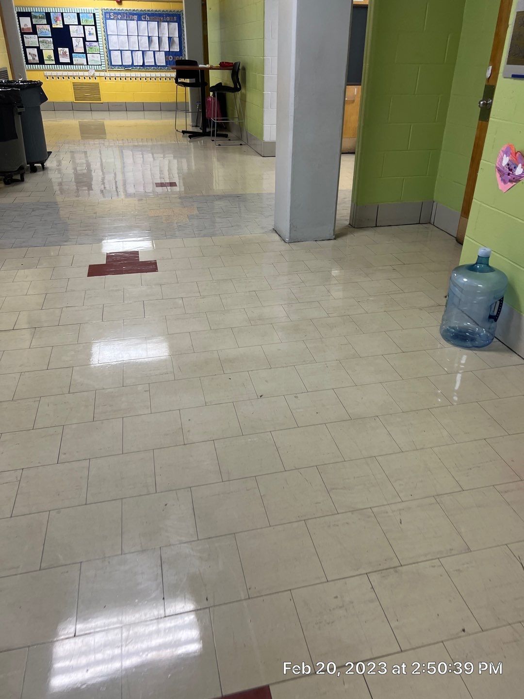 A bottle of water is sitting on the floor in a hallway.