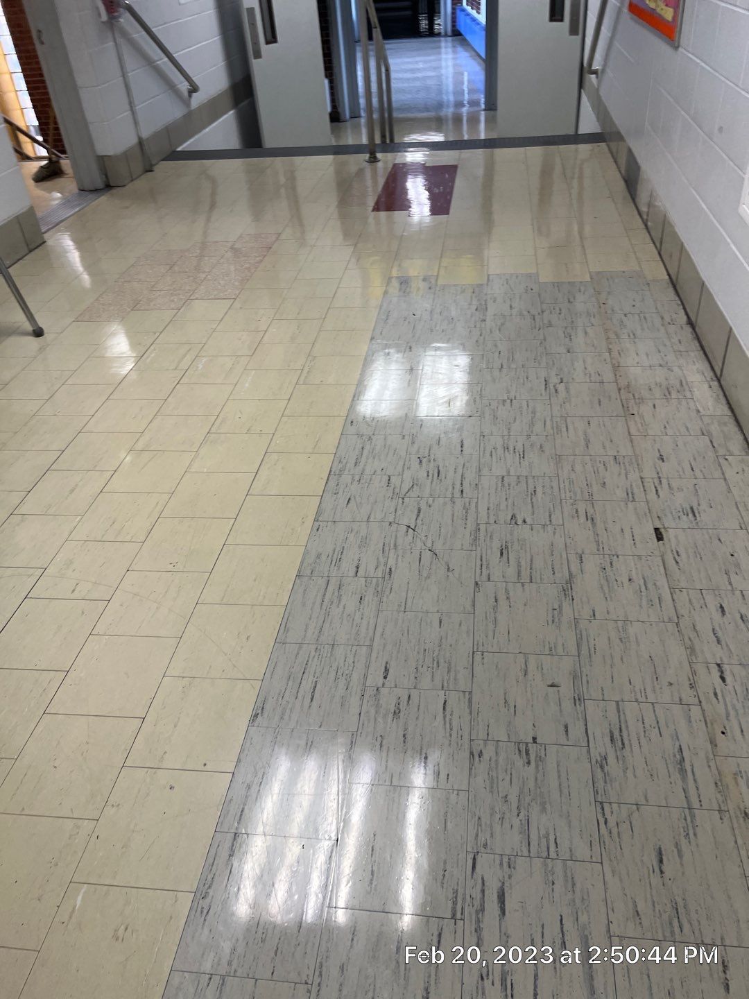 A hallway with a tiled floor and a reflection of a window.